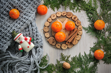 Fototapeta na wymiar Tangerines, scarf and spruce branches on a wooden background