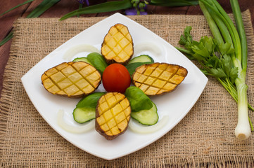 Baked potatoes with vegetables on the background color. Wooden table. Close-up