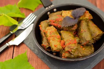 Dolma in the pan - this grape leaves stuffed with rice-based, as well  boiled minced meat. It is common in kitchens Caucasus, the Balkans, Asia and North Africa.Wooden background. Close-up