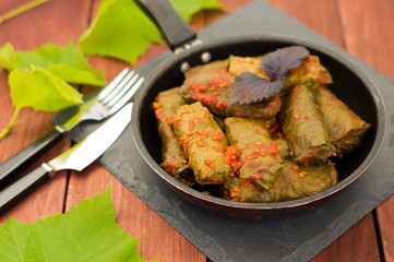 Dolma in the pan - this grape leaves stuffed with rice-based, as well  boiled minced meat. It is common in kitchens Caucasus, the Balkans, Asia and North Africa.Wooden background. Close-up