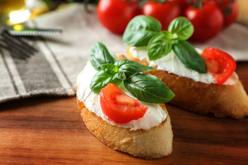 Delicious bruschetta with tomatoes on wooden table, closeup