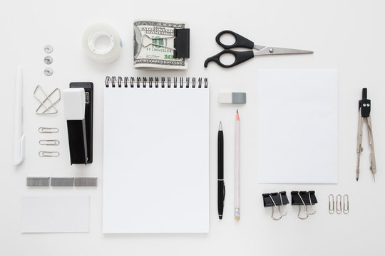 Set of black and white office supplies flat lay. Top view on various stationery on desk: notepads, pencils, scissors, stapler, clip, pins, pen, pencil and bundle of money. Business accessories mocup