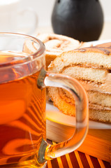 Transparent glass mug with hot tea and chocolate cake