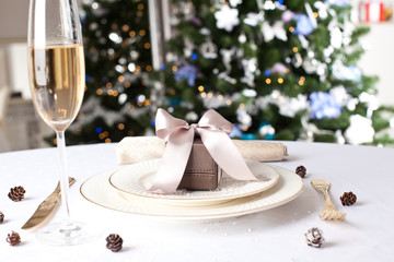 Gift on the beautiful table with Christmas tree on background.