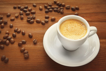 Cup of coffee and beans on wooden background