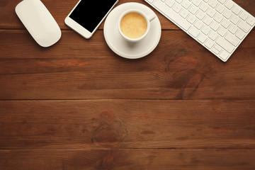 Computer keyboard, phone and cup of coffee on wooden background