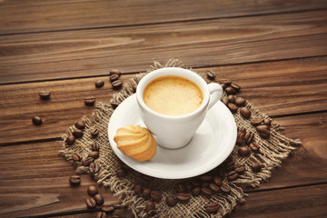 Cup of coffee and cookie on wooden background