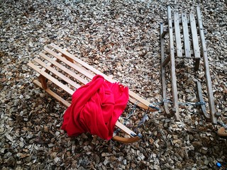 Schöne klassische Holzschlitten und Rodelschlitten mit roter Wolldecke auf Rindenmulch auf dem...