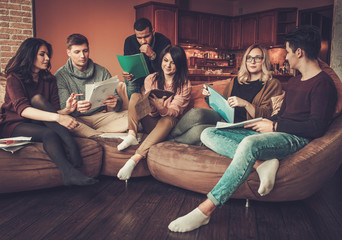 Group of multi ethnic young students preparing for exams in home interior