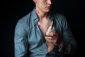 Drunk man with many lipstick stamps drinking wine