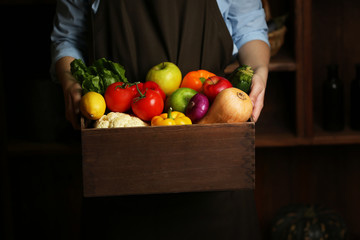 Obraz na płótnie Canvas Human hands holding wooden box with different fruits and vegetables closeup