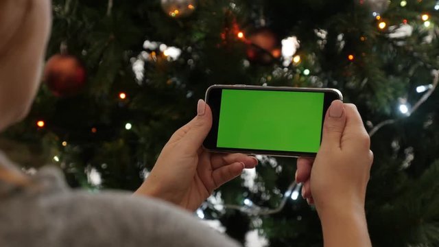 Green screen gadget in front of Christmas tree 4K 2160p 30fps UltraHD footage - Greenscreen display phone in woman hands 3840X2160 UHD video 