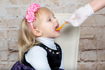 Doctor hand giving spoon dose of medicine liquid drinking syrup to child