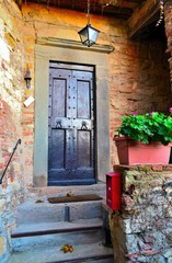 Fototapeta na wymiar vecchia porta di legno chiodata di un'abitazione toscana nel borgo medioevale di Montefioralle nel comune di Greve in Chianti, Firenze Italia 