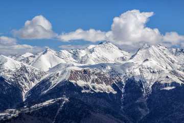 Beautiful snowy mountain peaks and blue sky with clouds scenic winter landscape of the Main Caucasus ridge