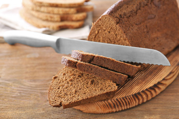 Sliced bread and knife on wooden cutting board closeup