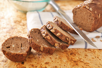 Sliced bread with seeds and knife on table closeup