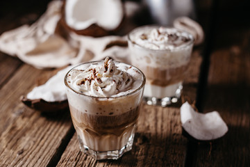 Coconut latte on a wooden table. Broken coconut. Low key food photo.