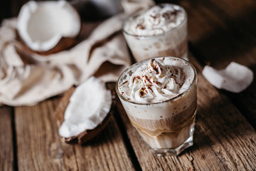 Coconut latte on a wooden table. Broken coconut. Low key food photo.