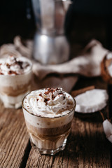 Coconut latte on a wooden table. Broken coconut. Low key food photo.