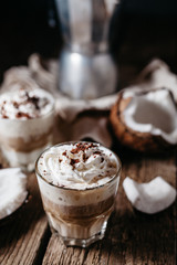 Coconut latte on a wooden table. Broken coconut. Low key food photo.