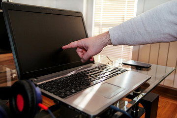 Fototapeta na wymiar Male hand forefinger about to tap a laptop screen te home