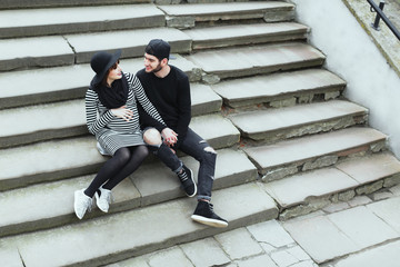 Man and pregnant girl sitting on stairs