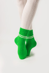 Female legs in white stockings and green knitted socks.
