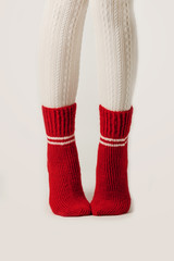 Female legs in white stockings and red knit socks.