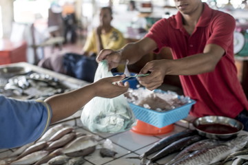 A fishmonger makes a sale in Kudat fish market, Sabah, Malaysian Borneo, Malaysia 