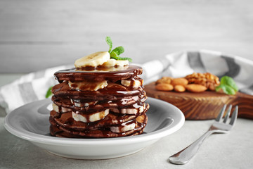 Tasty pancakes with banana and chocolate sauce on plate