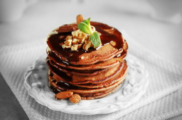 Tasty pancakes with nuts and chocolate sauce on plate