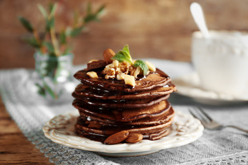 Tasty pancakes with chocolate sauce and nuts on plate