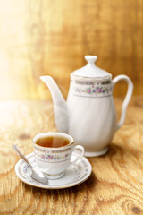 Vintage tea set with tea cup and teapot over wood table and wood background