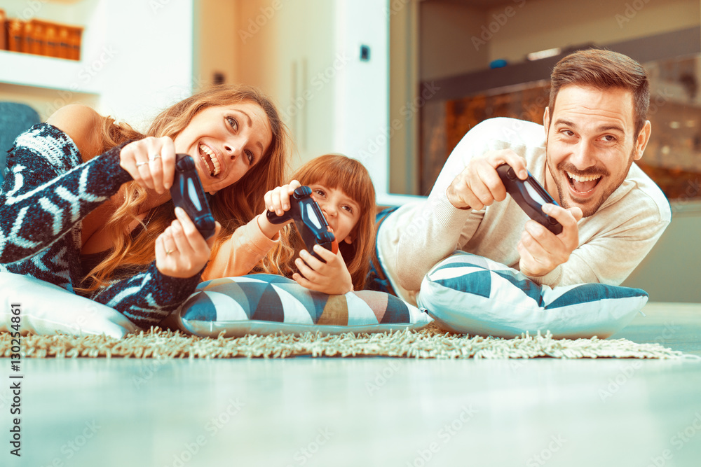 Wall mural Happy family playing a video game at home