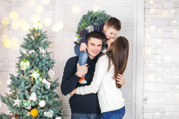 Family of mother, father and little child near Christmas tree with presents, decorations and New Year or Christmas