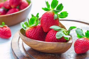 Ripe big strawberry close up in a wooden bowl, selective focus