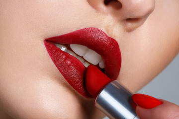 Close up portrait model applying dark red lipstick.. Professional fashion retro make-up.