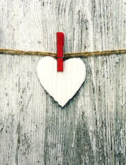 Paper white heart on a rope on grunge wooden background. Festive romantic image for Valentine's Day