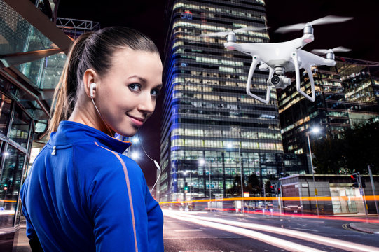 Hovering drone taking pictures of woman running in night city