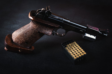 black pistol and cartridges on a black wooden table