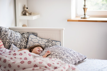 Little girl with smartphone lying in a bed, bedtime