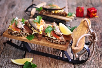 French toast with sprats, tomato, egg and garlic on a small wooden sled.