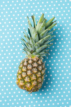 Overhead shot of fresh pineapple on blue dotted background