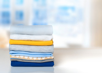 Stack cotton folded clothes on table indoors empty space.