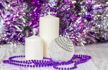 Silver Christmas ball, two white candles and purple beads