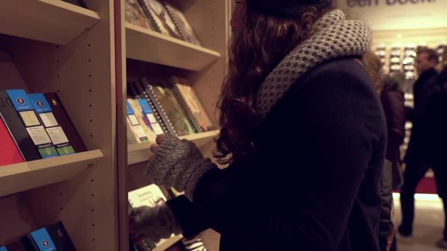 Young woman in a book store choose a book