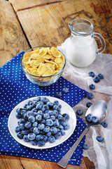Healthy breakfast with corn flakes, berries, milk on wooden background