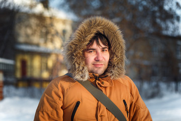 Portrait of the charming man who is smiling and talking on the phone in the winter cold day at sunset, dawn.