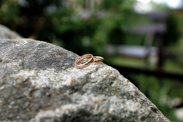 Wedding rings lie on a big stone lawn.